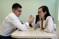 Young man and woman fight on his hands at the Desk in the office for a place Boss, head. The battle of the sexes, young couple hav Royalty Free Stock Photo