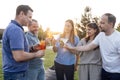 Young men and women are holding glasses with alcoholic beverages outdoors Royalty Free Stock Photo