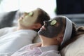 Young man and woman lying with cosmetic masks on their faces and cucumber slices on their eyes Royalty Free Stock Photo