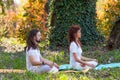 Young man and woman practice yoga meditation in nature side view full body shot in wood