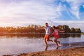 Young man and woman running on summer river bank. Happy couple having fun at sunset. Guys chilling Royalty Free Stock Photo