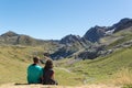 Young couple sitting down and looking at a valley in Pyrenees.