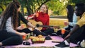 Young men and women are toasting and clinking glasses on picnic in park with guitar on warm autumn day. Friendship Royalty Free Stock Photo