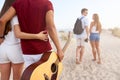 Group of friends going to sandy beach at sunset. Young men and women walking to the shore to relax near sea and play Royalty Free Stock Photo