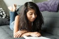 Young Mexicain woman reading a magazine. Home on a sofa