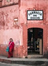 Young mexican girl leaning against the wall of a local pharmacy. Royalty Free Stock Photo