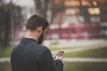 Handsome young man messaging a friend on his phone in an urban area Royalty Free Stock Photo