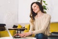 Young middle aged Caucasian woman with long hair. Casual clothes using laptop computer indoors. Cafe restaurant on chair wooden