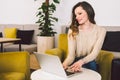 Young middle aged Caucasian woman with long hair. Casual clothes using laptop computer indoors. Cafe restaurant on chair wooden