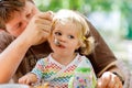 Young middle-aged father feeding cute little toddler girl in restaurant. Adorable baby child learning eating from spoon Royalty Free Stock Photo