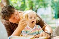 Young middle-aged father feeding cute little toddler girl in restaurant. Adorable baby child learning eating from spoon Royalty Free Stock Photo