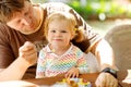 Young middle-aged father feeding cute little toddler girl in restaurant. Adorable baby child learning eating from spoon Royalty Free Stock Photo