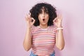 Young middle east woman standing over pink background looking surprised and shocked doing ok approval symbol with fingers Royalty Free Stock Photo