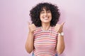 Young middle east woman standing over pink background success sign doing positive gesture with hand, thumbs up smiling and happy Royalty Free Stock Photo