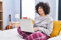 Young middle east woman using laptop drinking coffee sitting on bed at bedroom Royalty Free Stock Photo