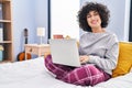 Young middle east woman using laptop drinking coffee sitting on bed at bedroom Royalty Free Stock Photo