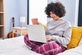 Young middle east woman using laptop drinking coffee sitting on bed at bedroom Royalty Free Stock Photo