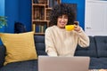 Young middle east woman using laptop and drinking coffee sitting on sofa at home Royalty Free Stock Photo