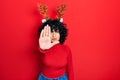 Young middle east woman wearing cute christmas reindeer horns doing stop sing with palm of the hand