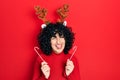 Young middle east woman wearing cute christmas reindeer horns winking looking at the camera with sexy expression, cheerful and Royalty Free Stock Photo