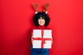 Young middle east woman wearing deer christmas hat holding gift winking looking at the camera with sexy expression, cheerful and Royalty Free Stock Photo