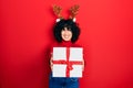 Young middle east woman wearing deer christmas hat holding gift winking looking at the camera with sexy expression, cheerful and