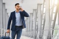 Young Middle-Eastern Businessman Walking With Suitcase In Airport And Talking On Cellphone Royalty Free Stock Photo