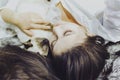 Young middle-eastern woman lying on bed and having fun with her Siamese cat. Pet loving concept. View from above to cute girl Royalty Free Stock Photo