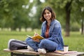 Young middle eastern woman writing in notebook while sitting on bench outdoors Royalty Free Stock Photo