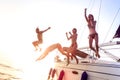 Young millenial friends jumping from sailboat at sea ocean trip - Guys and girls having summer fun together at sail boat party day