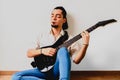 Young millenial man sitting on the floor of home playing an electric guitar Royalty Free Stock Photo