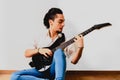 Young millenial man sitting on the floor of home playing an electric guitar Royalty Free Stock Photo