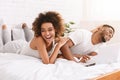 Young black couple lying on bed and using laptop.