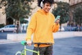 Young millennial biker listening playlist music with mobile phone app in the city - Focus on face