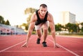 Young millennial determined muscular sportsman starting running on a red running court in a stadium - Athletic motivated runner Royalty Free Stock Photo