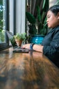 Young millennial working on laptop next to potted plant