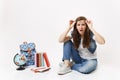 Young mistrustful puzzled woman student in denim clothes removing glasses sitting near globe, backpack, school books Royalty Free Stock Photo