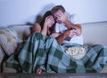 Young mixed race attractive couple with Asian Korean woman and white man enjoying together watching television horror movie scared Royalty Free Stock Photo