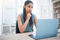 Young mixed race business woman concentrating on work while busy on laptop at her desk. Female entrepreneur sitting at Royalty Free Stock Photo