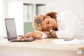 Young mixed race business woman sleeping in a office in front of a laptop on the desk. Latin female entrepreneur asleep Royalty Free Stock Photo