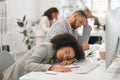 Young mixed race businesspeople sleeping at their desks while working in an office at work. Hispanic business Royalty Free Stock Photo