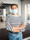 Young mixed race businesswoman standing with her arms crossed and wearing a mask at work. One hispanic female boss Royalty Free Stock Photo