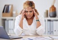 Young mixed race businesswoman suffering from a headache while sitting at a desk in an office at work. One stressed Royalty Free Stock Photo