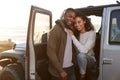 Young mixed race couple on a road trip embracing by car Royalty Free Stock Photo