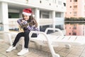 Young mixed race girl with guitar, sitting by swimming pool, with christmas santa hat, music concept Royalty Free Stock Photo