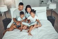 Young mixed race parents mom and dad reading a book to little daughter and son while bonding and spending time together Royalty Free Stock Photo