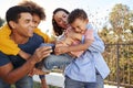 Young African American  parents playing outdoors carrying their children in the garden Royalty Free Stock Photo