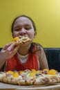 Young tween girl biting into candy and chocolate pizza