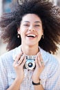 Young mixed race woman with curly hair taking creative photos on a vintage retro film camera. One female photographer