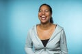 Young mixed race woman laughing a wide toothy smile being happy wearing casual clothing with a blue background Royalty Free Stock Photo
